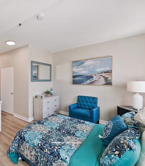 Bedroom with a blue floral bedspread at Azure Point at Encinitas - 55+ Active Adult Apartments, Encinitas