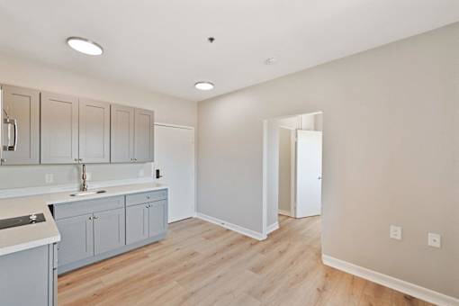 A kitchen with grey cabinets and a white counter top.