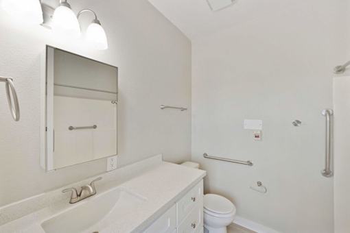 A white bathroom with a sink, toilet, and mirror.