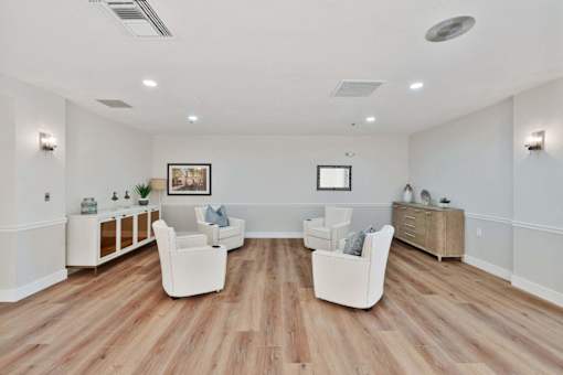 A spacious living room with white furniture and wooden flooring.