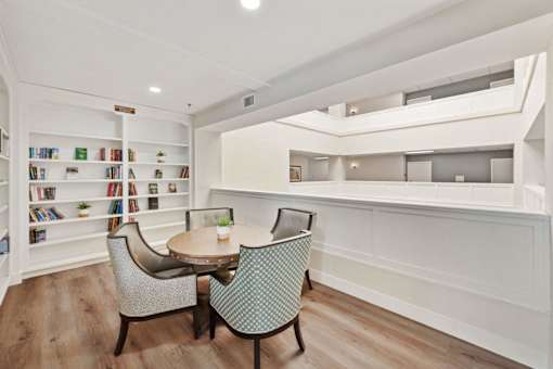 A white room with a table and chairs and a bookshelf.