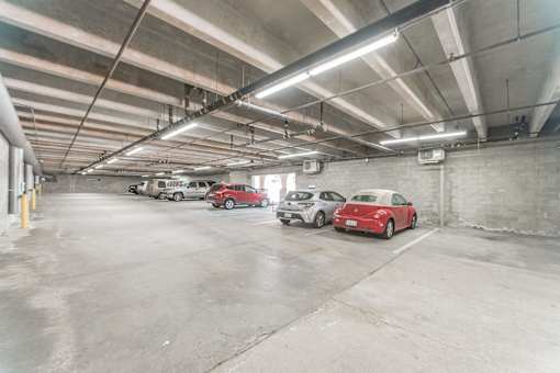 A parking garage with three cars parked in it.