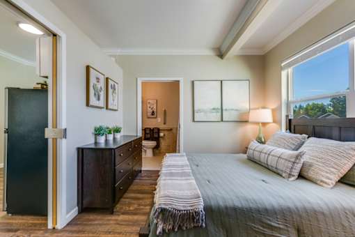 A bedroom with a large bed and a dresser with a mirror.