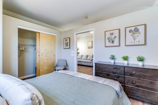 A bedroom with a bed, dresser, and chair.