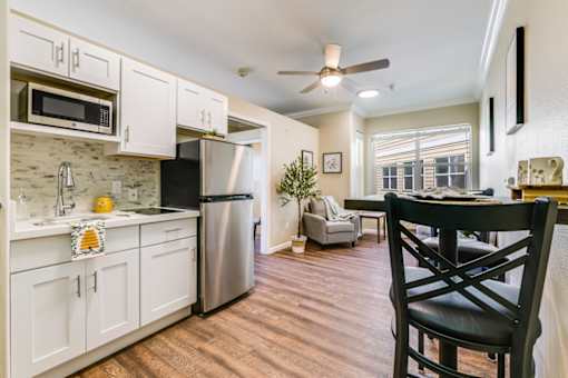 A kitchen with white cabinets and a black chair.