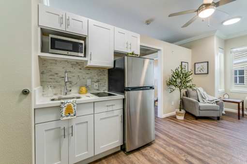 A kitchen with white cabinets and a stainless steel refrigerator.