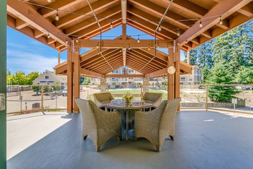A wooden pergola with a table and chairs is set up outside.