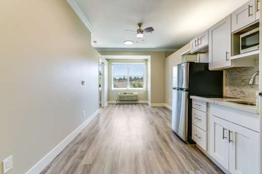 A kitchen with white cabinets and a black fridge.