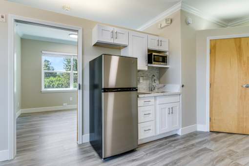 A kitchen with a black refrigerator, white cabinets, and a wooden door.
