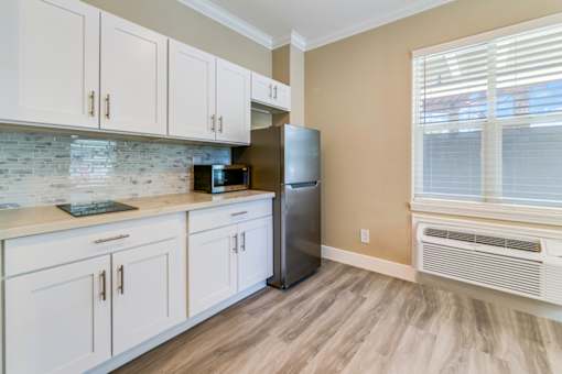 A kitchen with white cabinets and a black refrigerator.