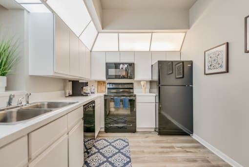 a kitchen with white cabinets and a black refrigerator