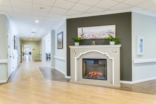A long hallway with a fireplace and a painting on the wall.