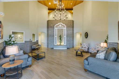 A spacious living room with a grey couch, a wooden table, and a chandelier.