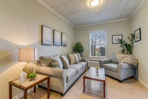 A living room with a grey couch, a coffee table, and a lamp.