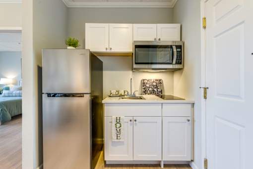 A kitchen with a refrigerator, cabinets, and a microwave.