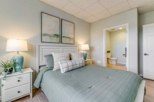 A bedroom with a large bed and two lamps.