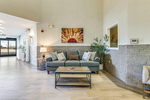 A living room with a grey couch and a stone wall.