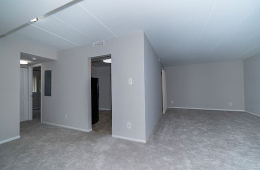 A large empty room with white walls and carpeted floor.