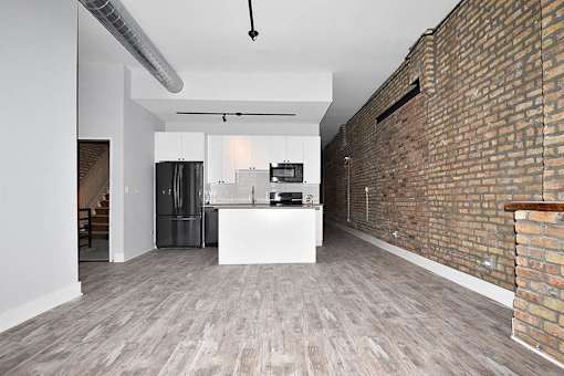 A kitchen with a white island and a brick wall.