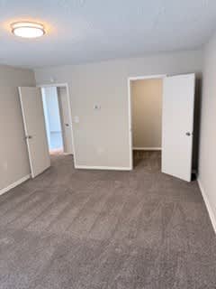 A bedroom with carpeted floor and three doors.
