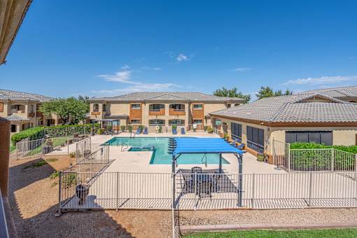 A sunny day at a residential complex with a pool and a fence.