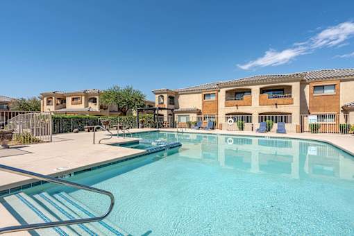 A swimming pool in front of a building with a clear blue sky.