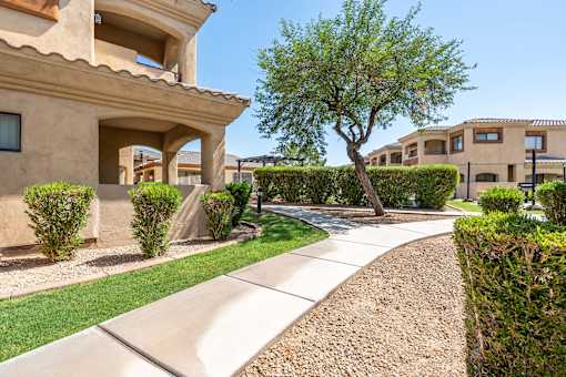 A beige house with a tree in front of it.