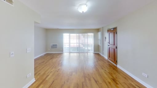 an empty living room with a large window and hardwood floors