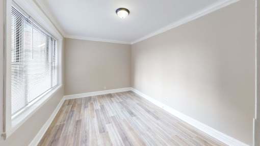 A room with a window and wooden flooring.