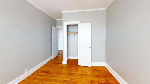 A room with a wooden floor and white walls with two doors.