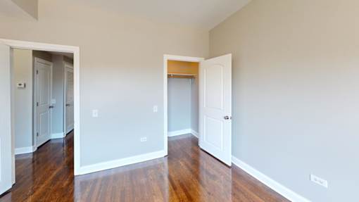 A room with white walls and wooden floors with two doors.