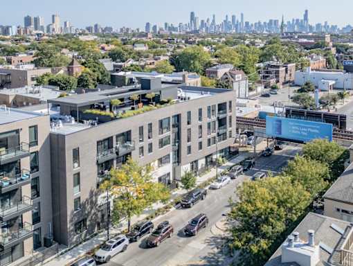 an aerial view of an apartment building with a city skyline in the background