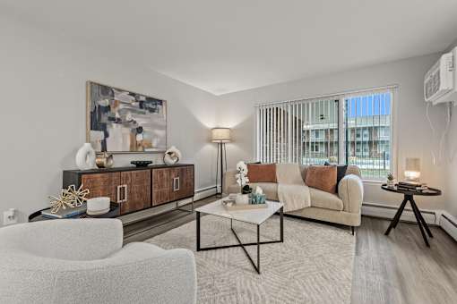 A modern living room with a white sofa, a coffee table, and a large painting on the wall.