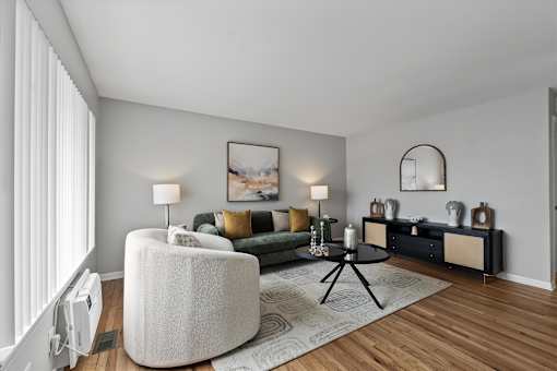 A modern living room with a white sofa, a green couch, and a large painting on the wall.