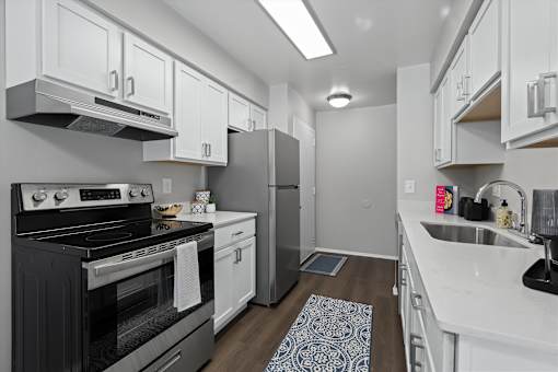 A modern kitchen with a black stove top oven and white cabinets.