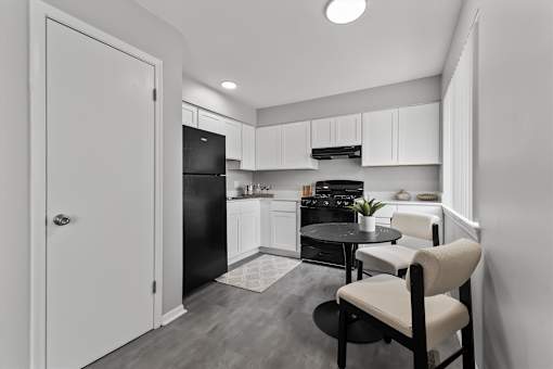 A black and white photo of a kitchen with a table and chairs.