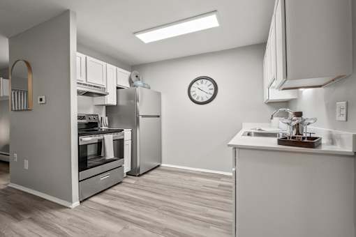 A modern kitchen with a stainless steel refrigerator and a wooden floor.