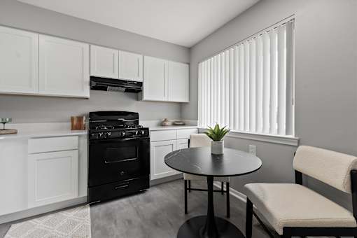 A black oven sits in a kitchen with white cabinets and a round table.