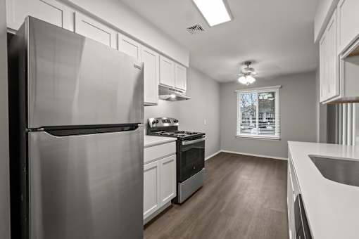 A modern kitchen with a stainless steel refrigerator and wooden flooring.