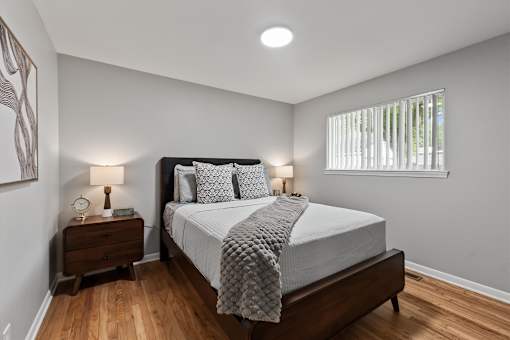 A bedroom with a bed, nightstand, and window.