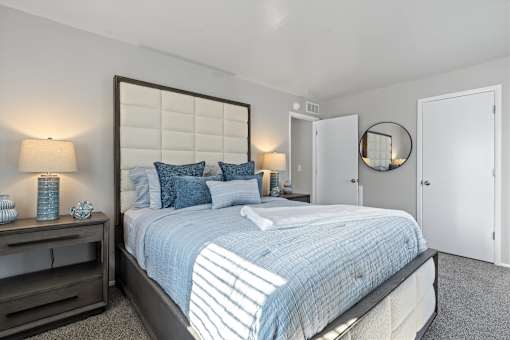 A bedroom with a large bed and a mirror on the wall.