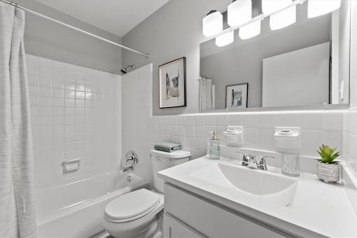 A white bathroom with a toilet, sink, and mirror.