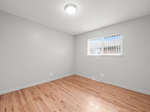 a bedroom with a hardwood floor and a large window