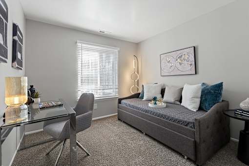 A grey bedroom with a bed, desk, and chair.