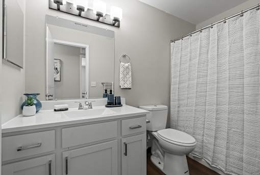 A white bathroom with a toilet, sink, and shower curtain.
