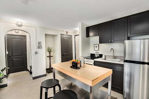 A kitchen with a wooden table and black stools.