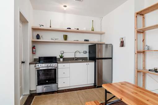 A kitchen with a stove, oven, refrigerator, and a wooden table.