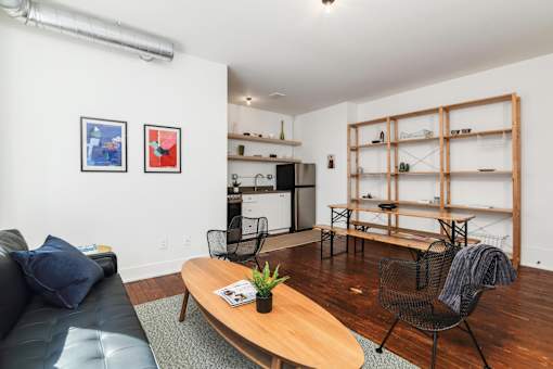 A living room with a black leather couch, a wooden coffee table, and a chair.