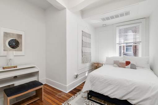 A bedroom with a large bed and a desk with a lamp.