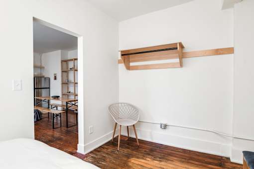 A room with a white chair and a wooden shelf.